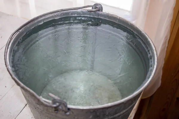 Bucket of water on the table in the cold. Close-up of an ice bucket on the background.