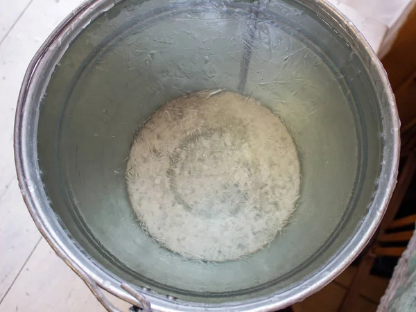 Bucket of water on the table in the cold. Close-up of an ice bucket on the background.