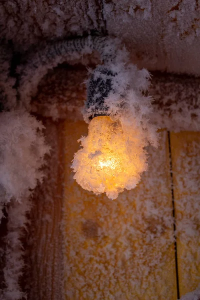 Sneeuwkristallen op een houten muur en een gloeilamp. — Stockfoto