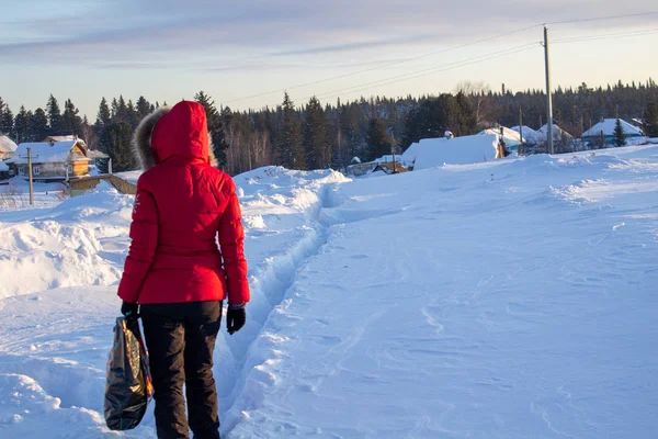 Ένα κορίτσι με κόκκινο μπουφάν περπατά μέσα από χιονοστιβάδες στη Σιβηρία της Ρωσίας.. — Φωτογραφία Αρχείου
