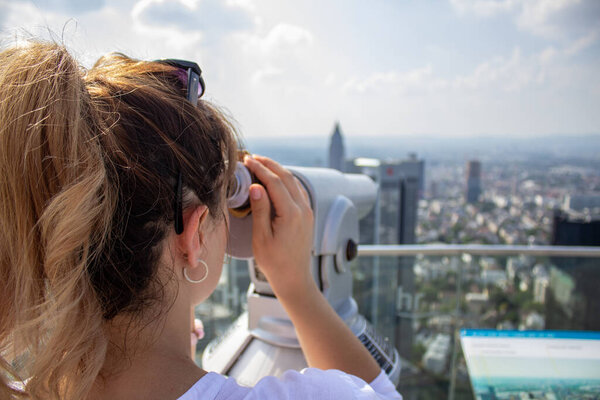 Young tourist girl with looking at the Frankfurt from the top of the main tower. Aerial View Frankfurt am Main from main tower to financial center