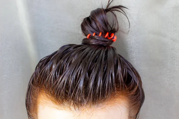 Cuidados com o cabelo em casa. A menina aplicou o bálsamo em seu cabelo e reuniu seu cabelo em um pão . — Fotografia de Stock