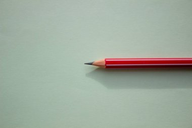 Açık yeşil arkaplanda bir kırmızı kalem.