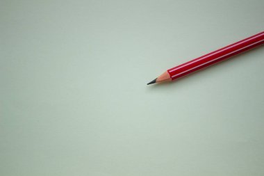 Açık yeşil arkaplanda bir kırmızı kalem.