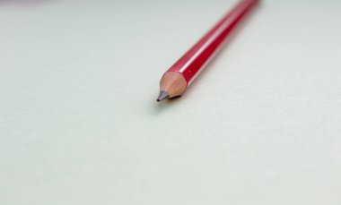 Açık yeşil arkaplanda bir kırmızı kalem.