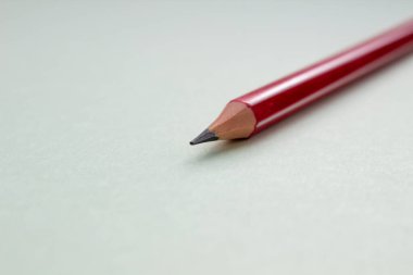 Açık yeşil arkaplanda bir kırmızı kalem.