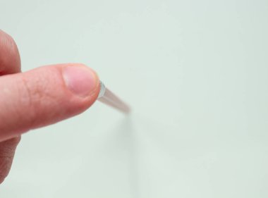 Bir adam kırmızı kalemi parmaklarıyla hafif bir kağıtta tutuyor..