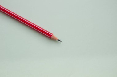 Açık yeşil arkaplanda bir kırmızı kalem.