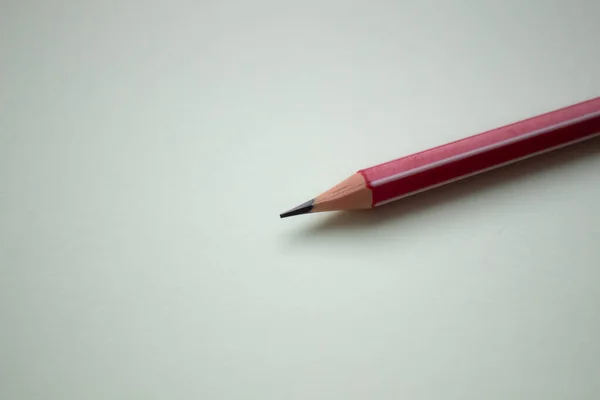 Um lápis vermelho em um fundo verde claro . — Fotografia de Stock