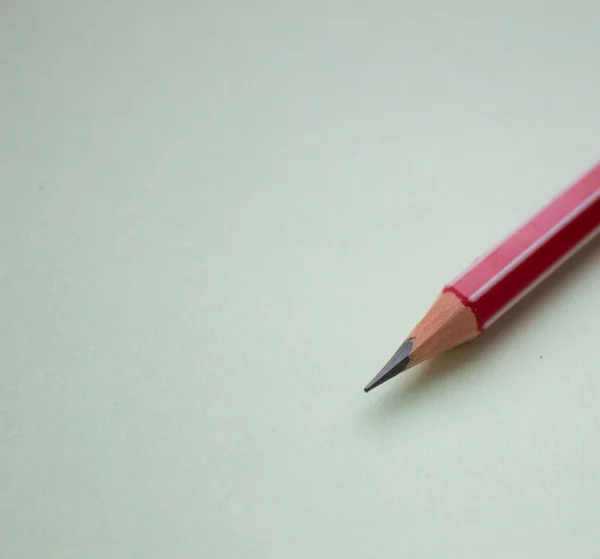 Один червоний олівець на світло-зеленому тлі . — стокове фото