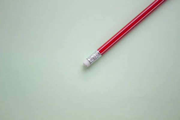 Один красный карандаш на светло-зеленом фоне . — стоковое фото
