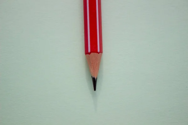 Jeden czerwony ołówek na jasnozielonym tle. — Zdjęcie stockowe