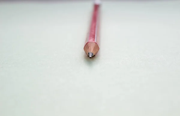 Un lápiz rojo sobre un fondo verde claro . — Foto de Stock