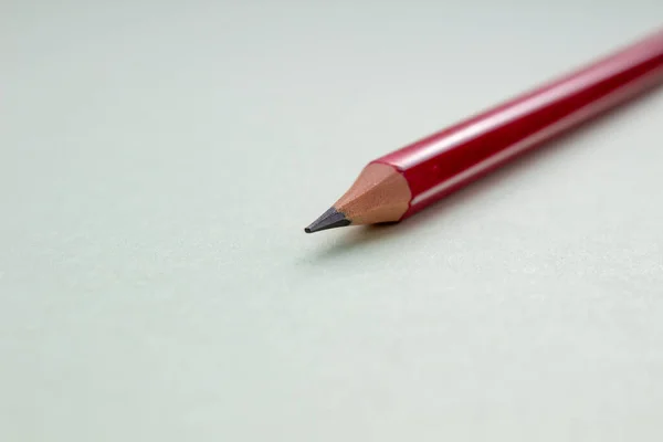 Egy piros ceruza világoszöld háttérrel. — Stock Fotó