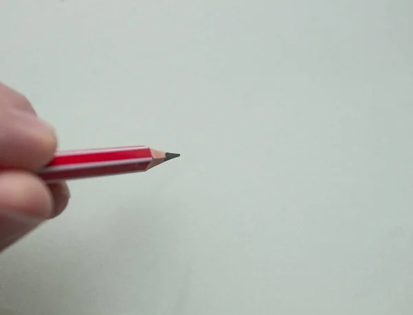 Ένας άντρας κρατά ένα κόκκινο μολύβι σε ένα ελαφρύ χαρτί με τα δάχτυλά του.. — Φωτογραφία Αρχείου