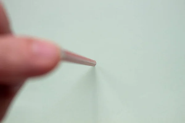 Ein Mann hält mit seinen Fingern einen Rotstift auf ein helles Papier. — Stockfoto