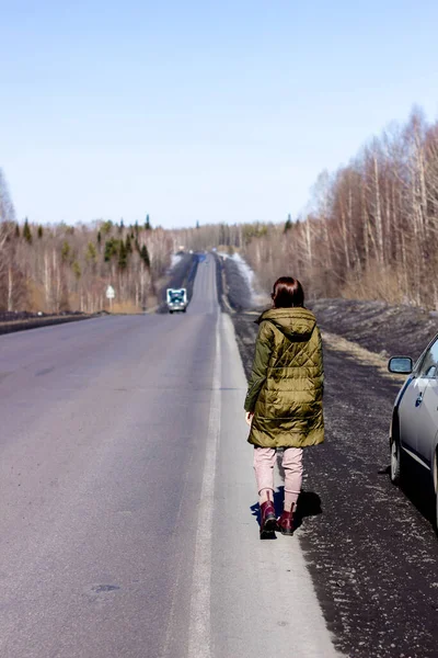 一个年轻的女人走在路边 森林中的道路 — 图库照片