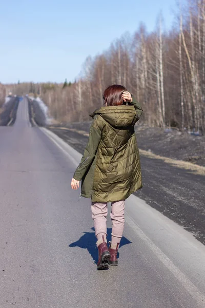 Uma jovem caminha ao lado da estrada. Estrada na floresta — Fotografia de Stock