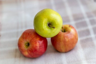 Üç elma, bir yeşil ve iki kırmızı-sarı arka planda