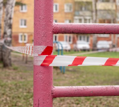 Moskova, Rusya, 2020: salgın, koronavirüsü durdurun, evde kalın. Oyun parkı salıncağı kırmızı kurdeleyi yasaklıyor, Coronavirus covid-19 sars virüsünün enfeksiyonunu önlüyor. Beyaz ve kırmızı bir kurdele oyun parkına girmemizi yasaklıyor. Oyun alanı salıncağı