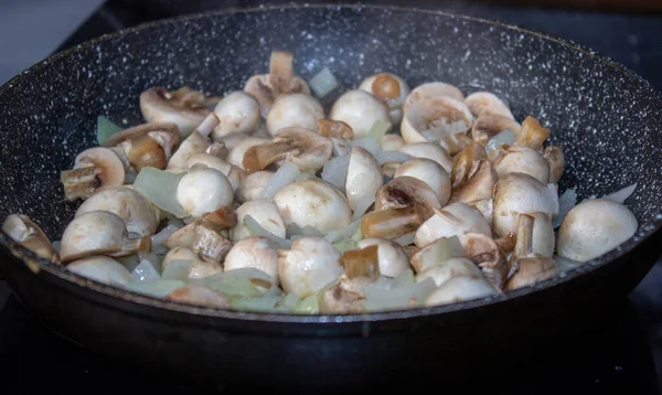 Mushrooms with onions in a frying pan. Preparing lunch and dinner. — Stock Photo, Image