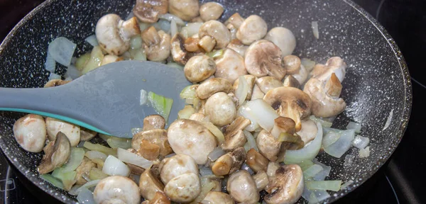 Mushrooms with onions in a frying pan. Preparing lunch and dinner. — Stock Photo, Image