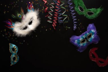 Siyah arka planda karnaval nesneleri. Sarılmış flamalar, maskeler, konfetiler.