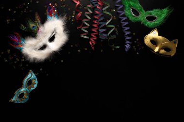 Siyah arka planda karnaval nesneleri. Sarılmış flamalar, maskeler, konfetiler.