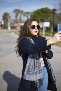 Business woman takes selfies in a warm winter day