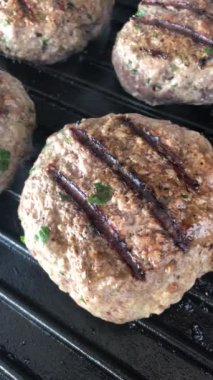 Açık ateşte pişen sulu burgerler. Propan gazı alevlerinde ızgara yapan lezzetli hamburgerler dökme demir ızgarada.