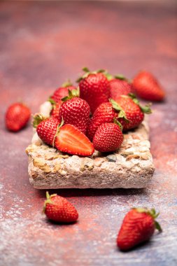 Kırmızı, taze ve lezzetli çilekler bir taşta ve kırmızı arka planda