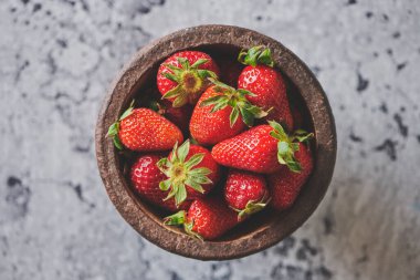 Çimento arka planında seramik kasede taze çilek yığını