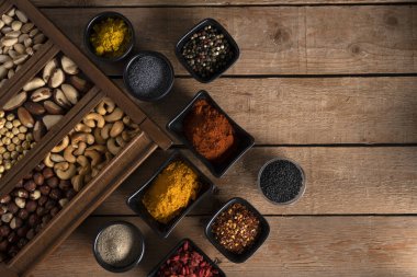 Ceviz, fındık, köpek çekirdekleri, siyah susam tohumları, beyaz biber, kırmızı biber, köri, sarımsak ve daha fazlası ahşap bir yüzeyde.