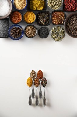 Beş küçük gümüş kaşık körili, kırmızı biberli, kırmızı biberli, biberli ve kişniş karışımı aynı baharatlı farklı kase şeklindeki farklı baharatlarla.