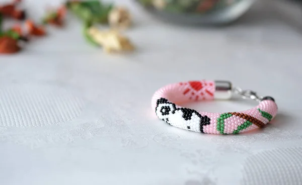 Pink beaded bracelet with the image of a panda close up