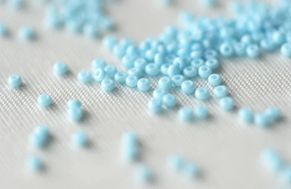 Scattered seed beads of light blue color close up