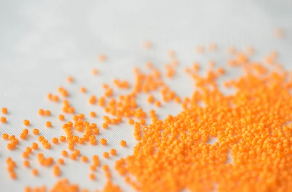 Seed beads of orange color on textile background