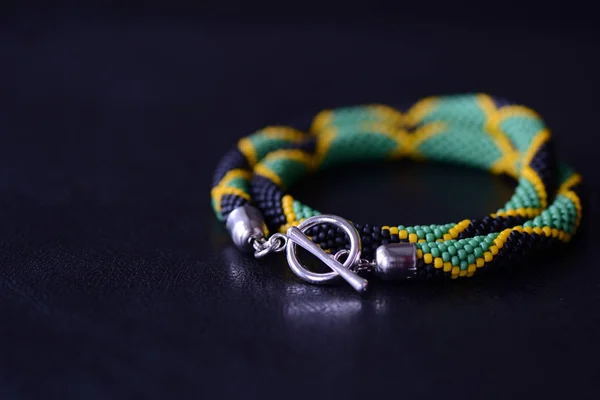 Seed beads necklace Jamaican flag on a dark background close up