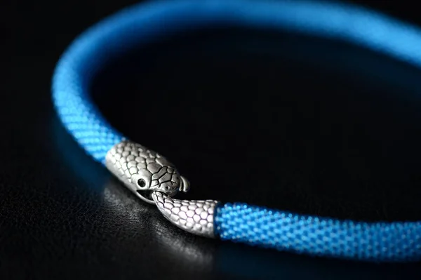 Blue beaded necklace with snake head lock on a dark background close up