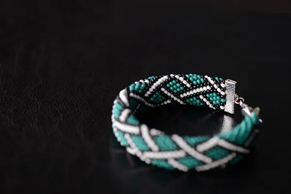 Green bead crochet bracelet with celtic print on a dark background close up