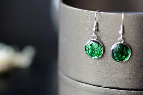 Green resin earrings on a dark background close up