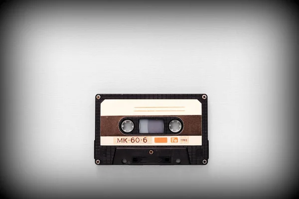 Audio tape cassette on a gray background close-up, top view. Old Technology Concept