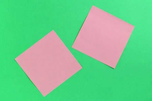 Empty pink sticker notes on a green background. Business concept, horizontal mock-up