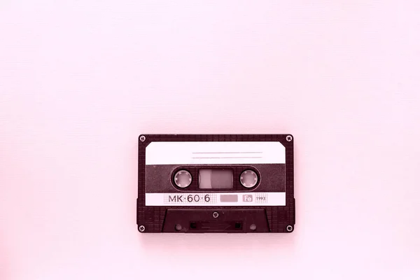 Old audio tape cassette close-up. Old technology concept. Pink color toned