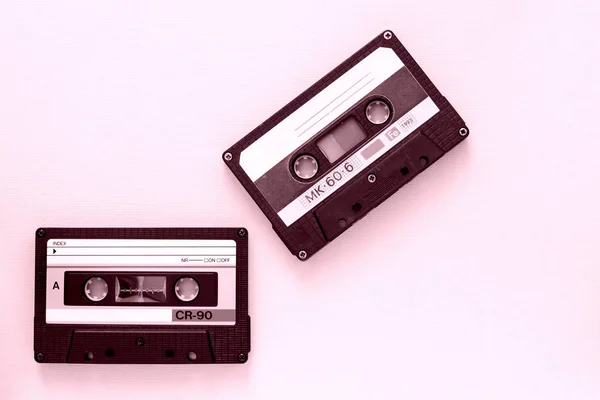 Two old audio tape cassettes close-up. Old technology concept. Pink color toned