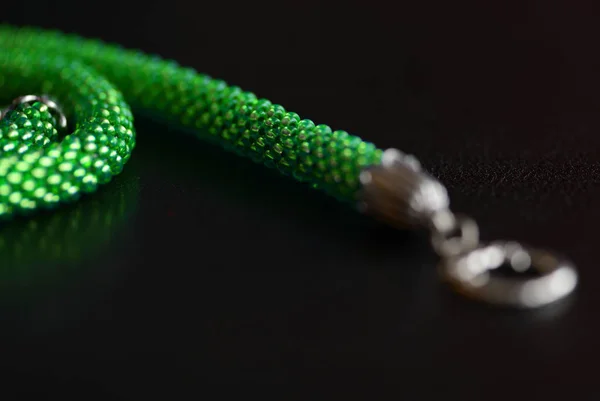 Light green beaded necklace on a dark surface close-up. Fashion background