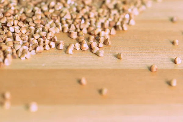 Buckwheat scattered on a wooden surface close-up. Healthy food background retro style toned