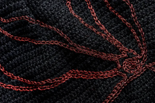 Close-up of a black crocheted bag with embroidery red thread. Hand made concept. Top view