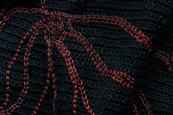 Close-up of a black crocheted bag with embroidery red thread. Hand made concept. Top view