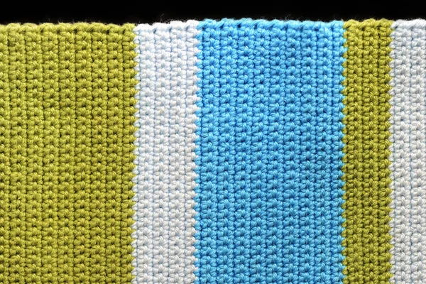 Crocheted fabric from multi-colored yarn close-up, top view. Abstract background. Hand made concept